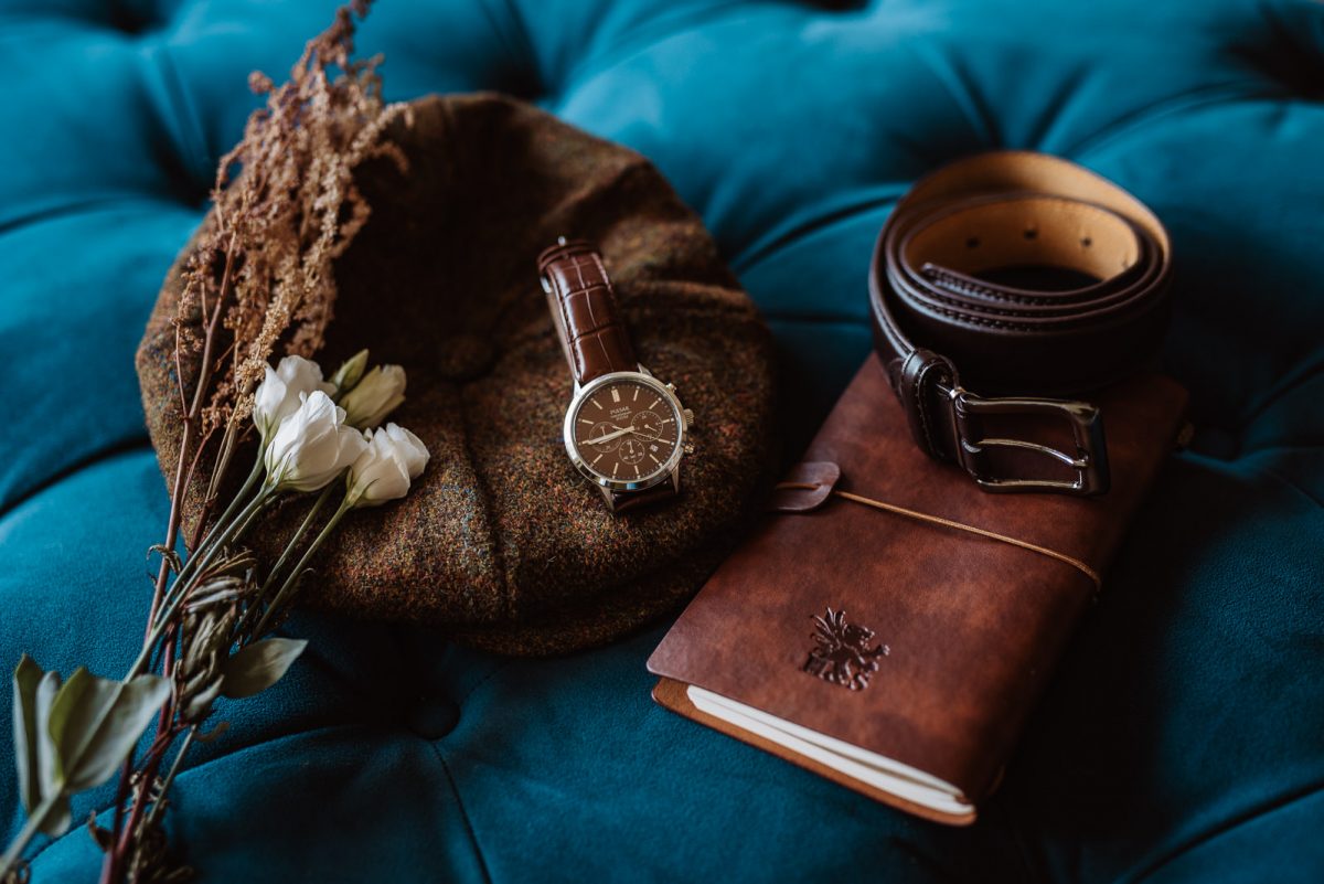 Details of the accessories for the groom. A book for the vows in leather, a belt, watch and hat.