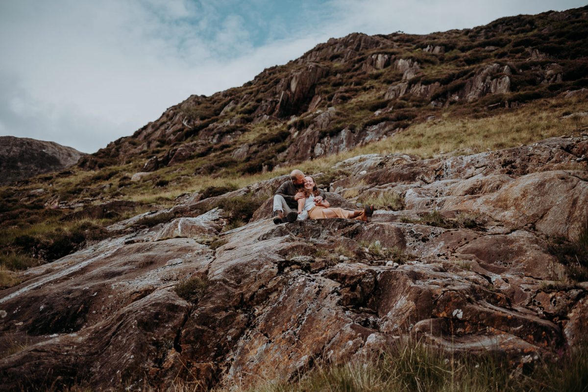 Mountain elopement. Lovely couple sitting on the rocks and cuddling.