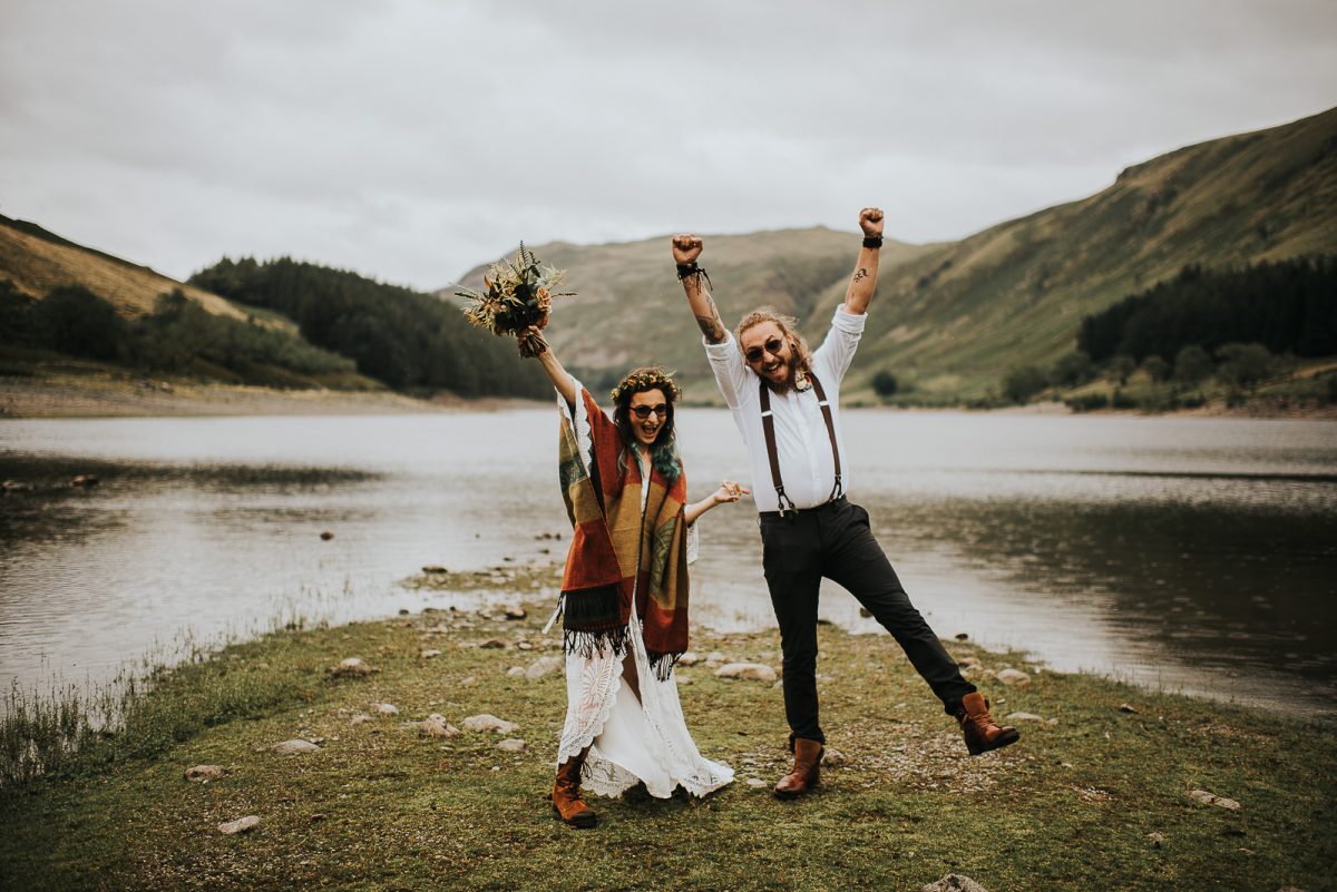 A couple eloping into the wild in Lake District. They are standing close to each other, smiling and buzzing as they are happy to be just married
