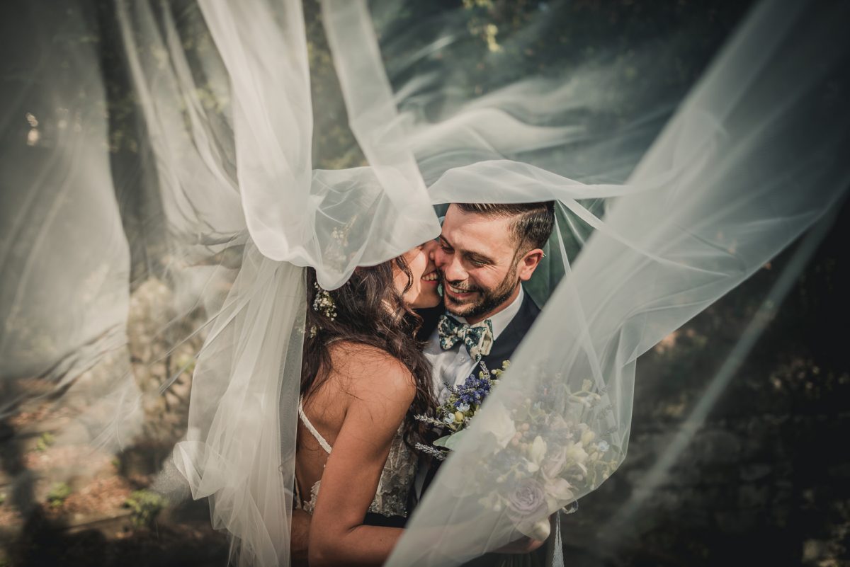 Couple laughing and hugging each other under the bride veil.