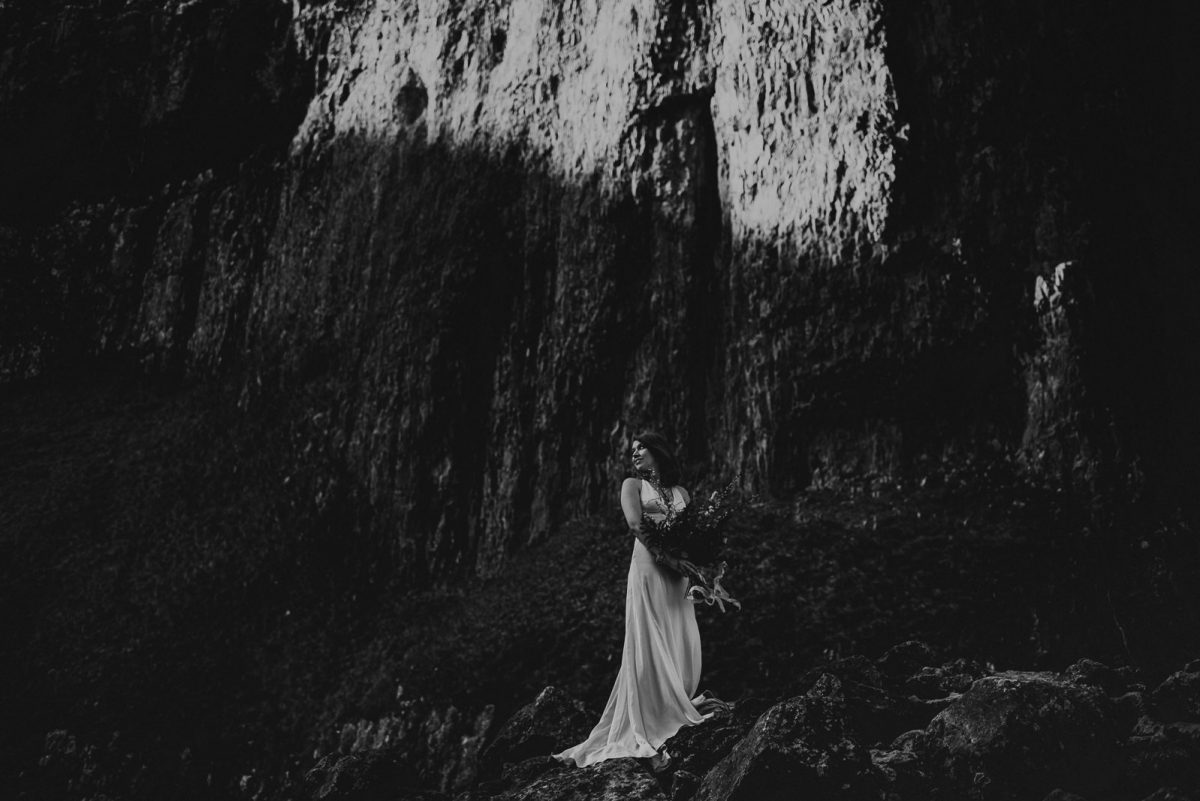 Bride standing on the rocks with a beautiful bouquet.