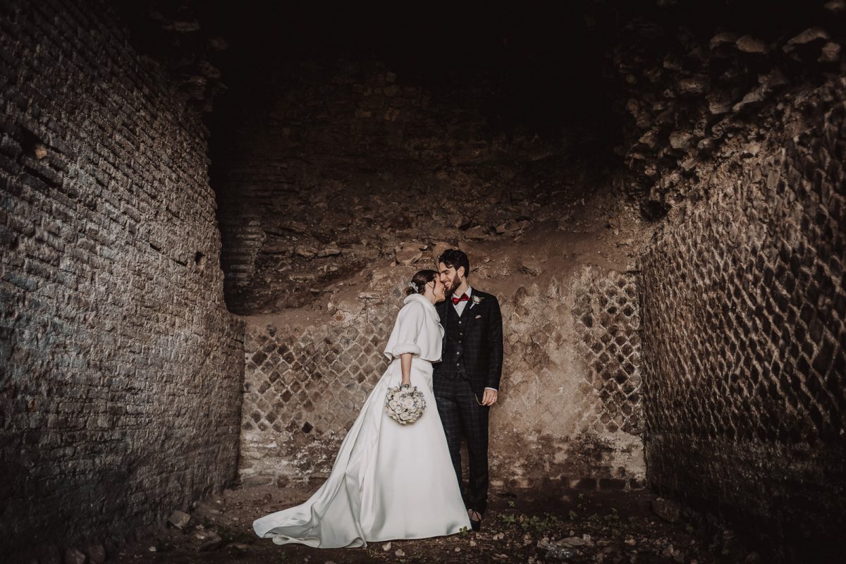 Couple standing inside a little cave. Winter elopement in Italy.