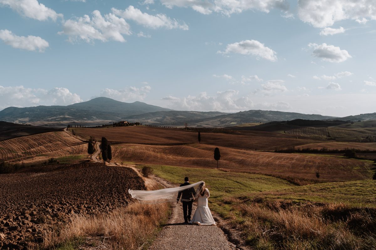 Couple walking across fields in Tuscany Italy